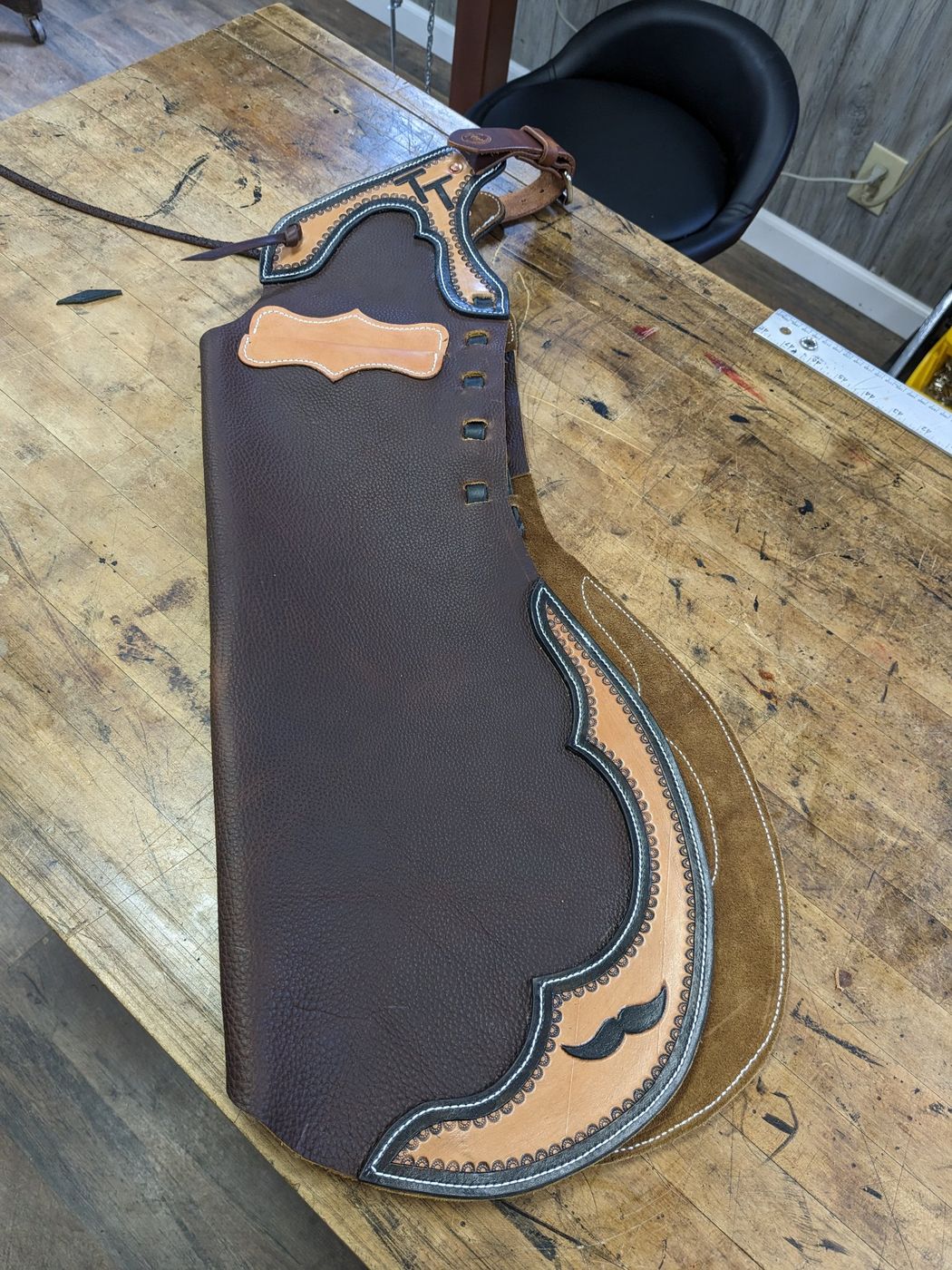 Brown leather chap with TT brand on workbench