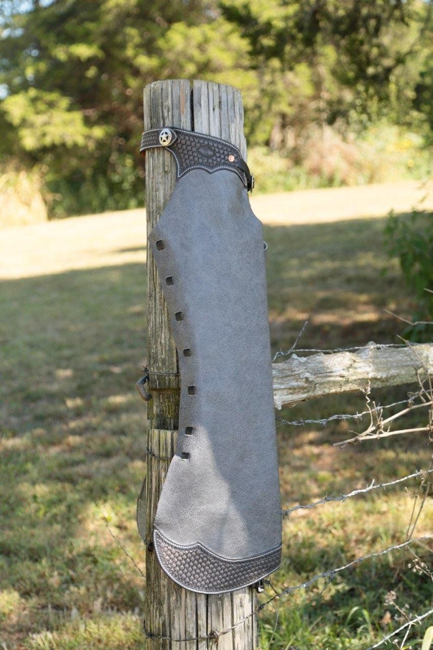 Gray roughout chap hanging on a fence post